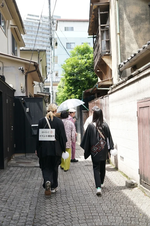 石畳の路地裏を和服姿のグループが歩いている様子