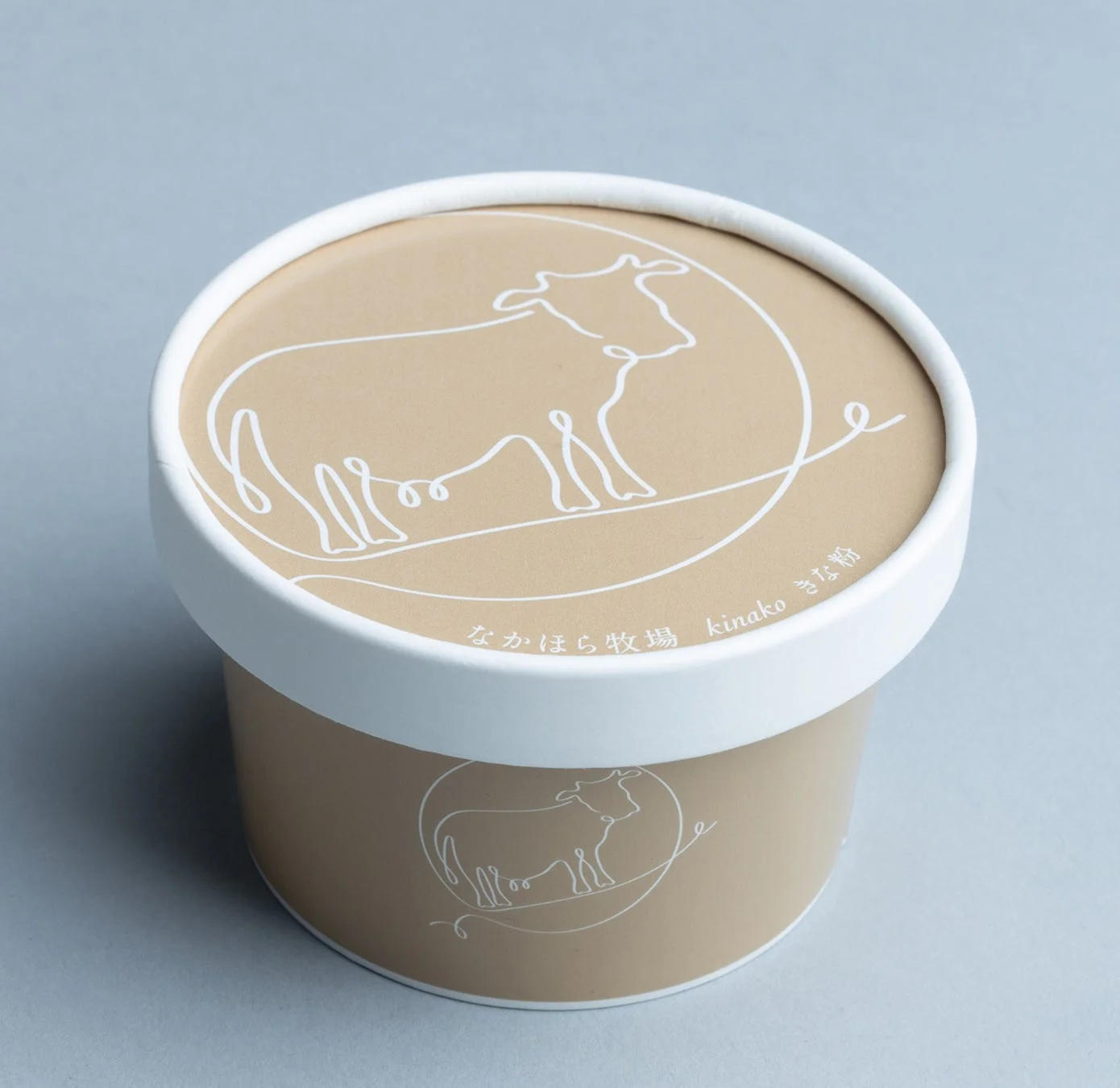 牛のイラストが描かれたベージュ色のきな粉の容器です。蓋には「なかほら牧場 kinako きな粉」と記載されており、牧場由来の製品であることがわかります。