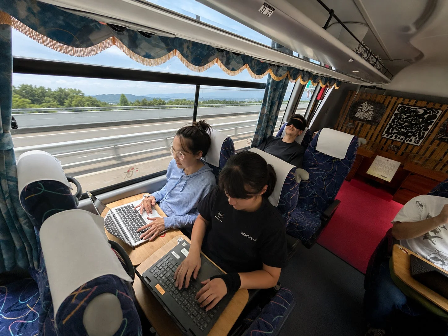 高速道路を走行中のバス車内で作業や休憩をする乗客