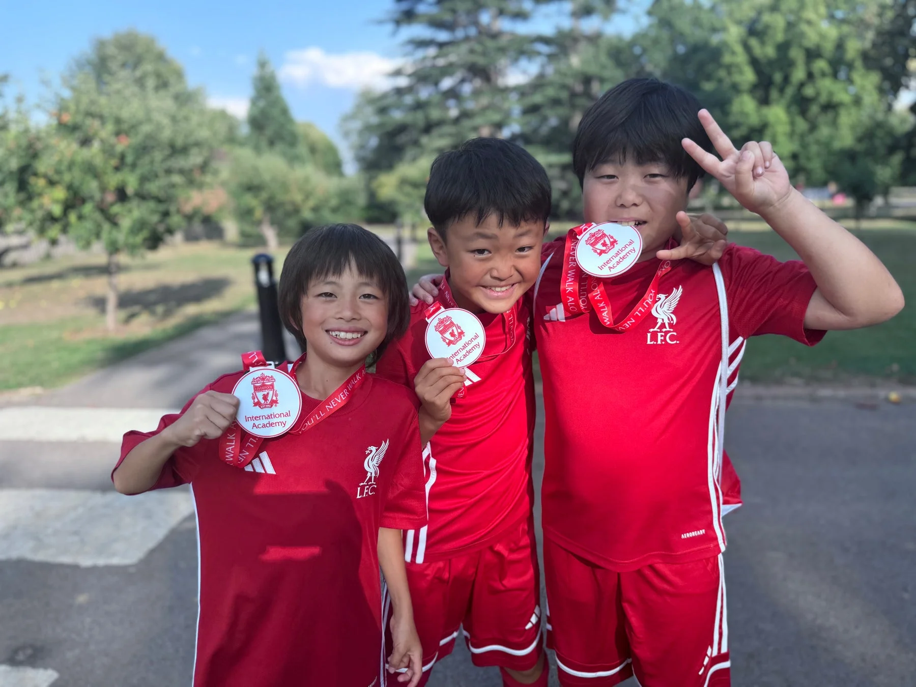 メダルを持つリバプールFCユニフォームの子供たち