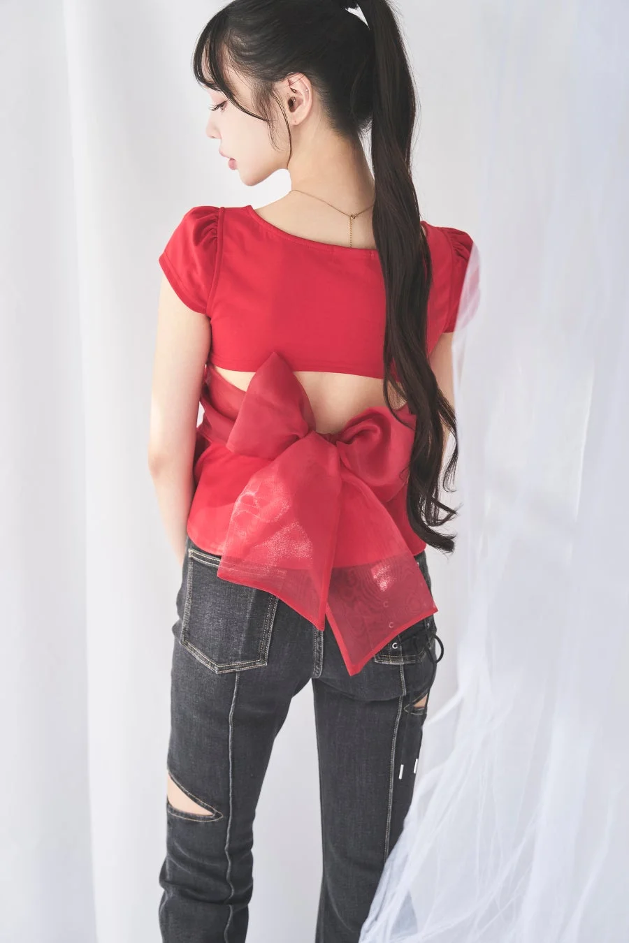 赤いトップスにリボンがあしらわれたスタイリングの中村里砂さん