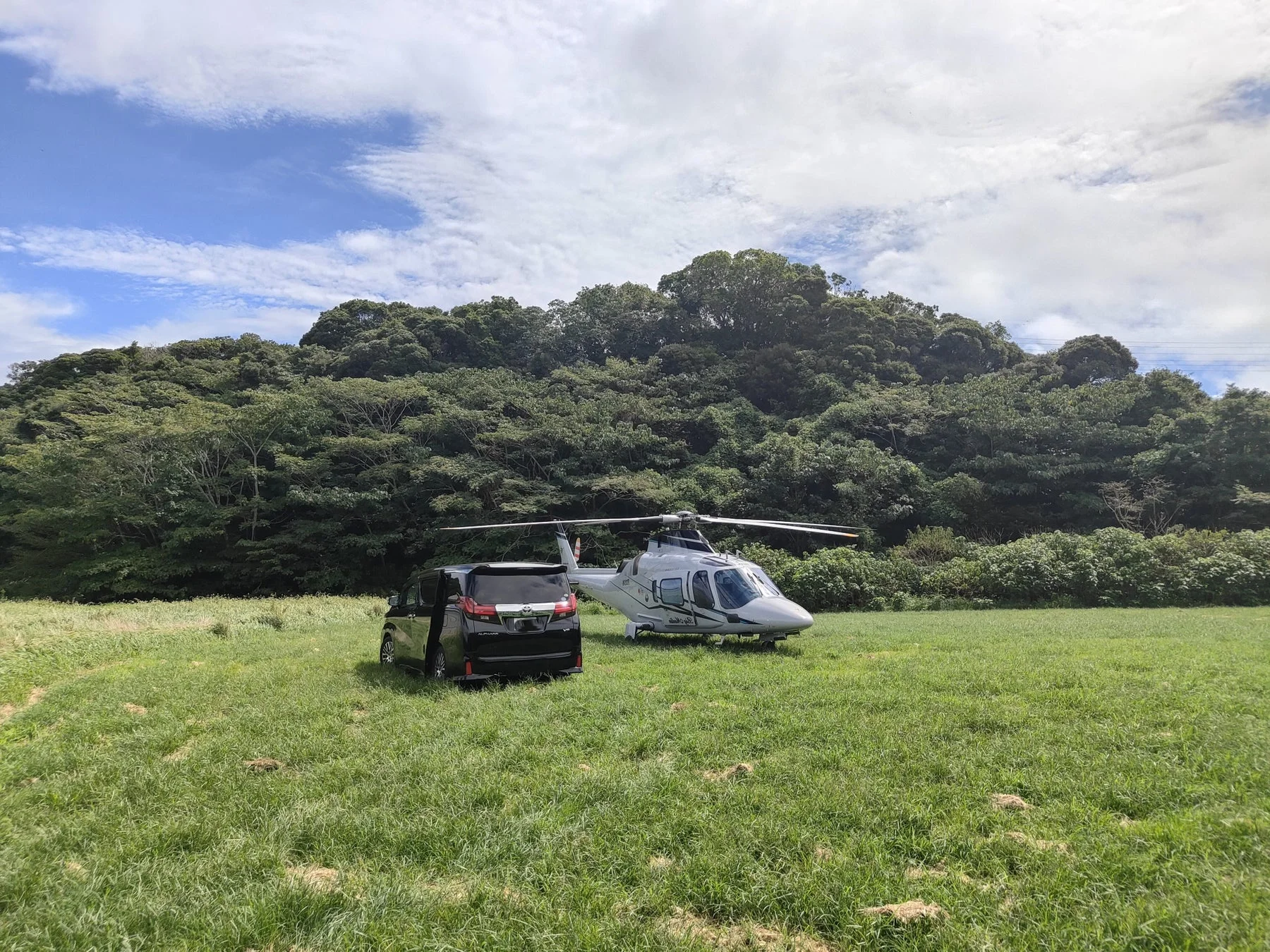ヘリコプターとバンが停まる広大な草原