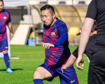 バルセロナのユニフォームを着てサッカーグラウンドでプレイする小林耕平選手