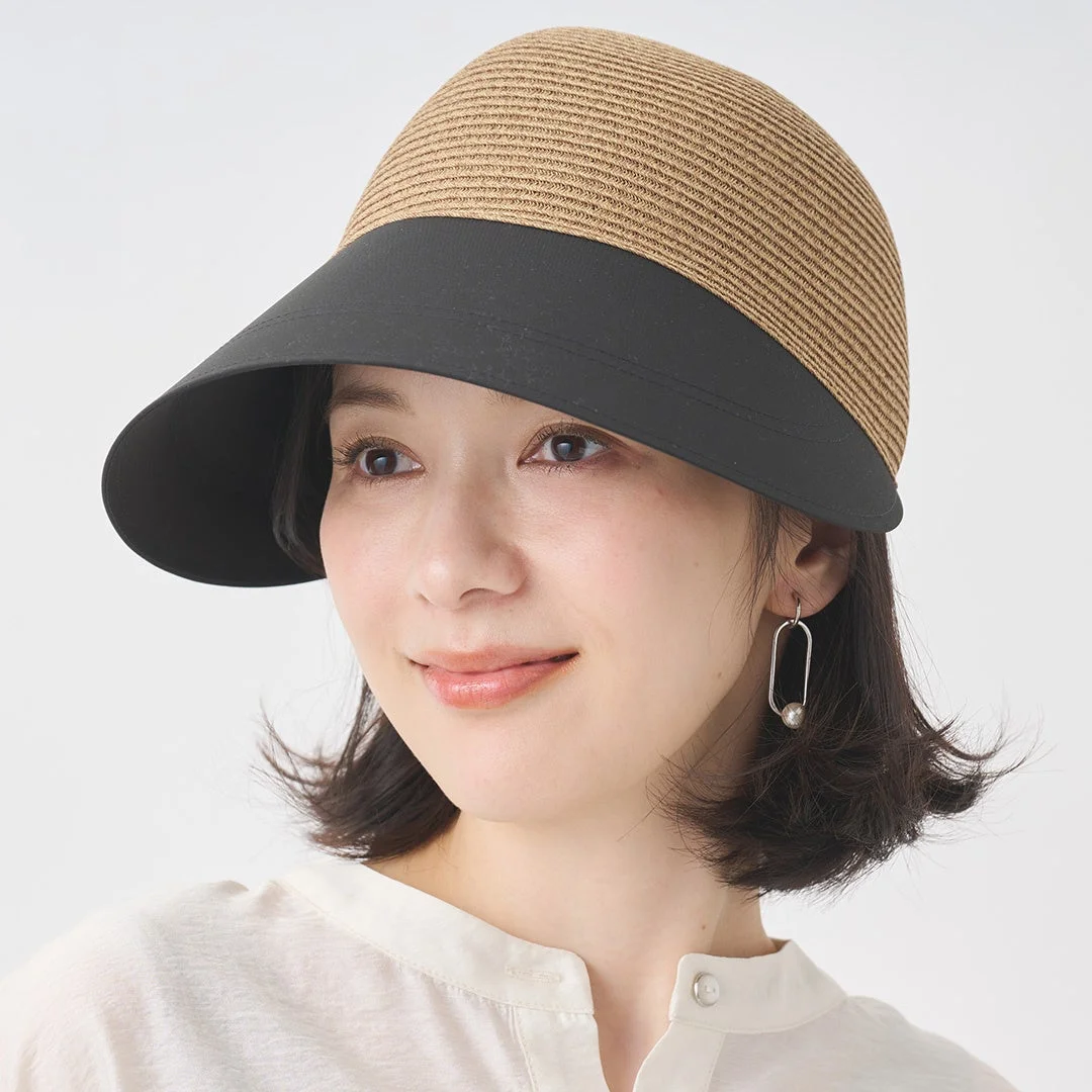 ベージュの編み込みと黒いツバが特徴的な帽子を被った女性のポートレートです