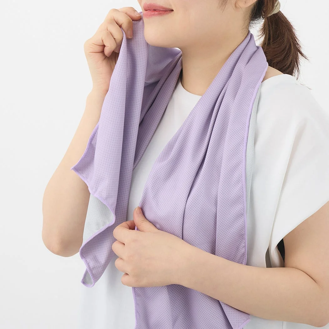白いTシャツを着た女性が、首元に紫色の冷却タオルを巻いている様子です