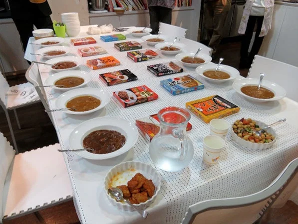 様々なレトルトカレーが並べられ、食べ比べが行われている様子