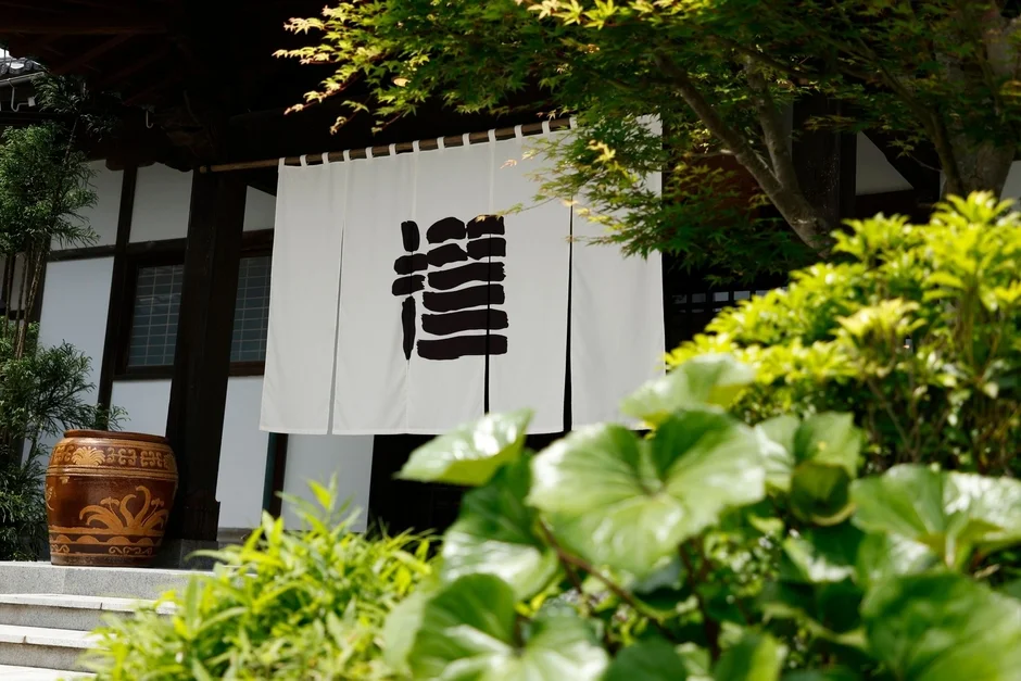 「龍」の文字が描かれた白い暖簾がかかる伝統的な日本家屋の入り口