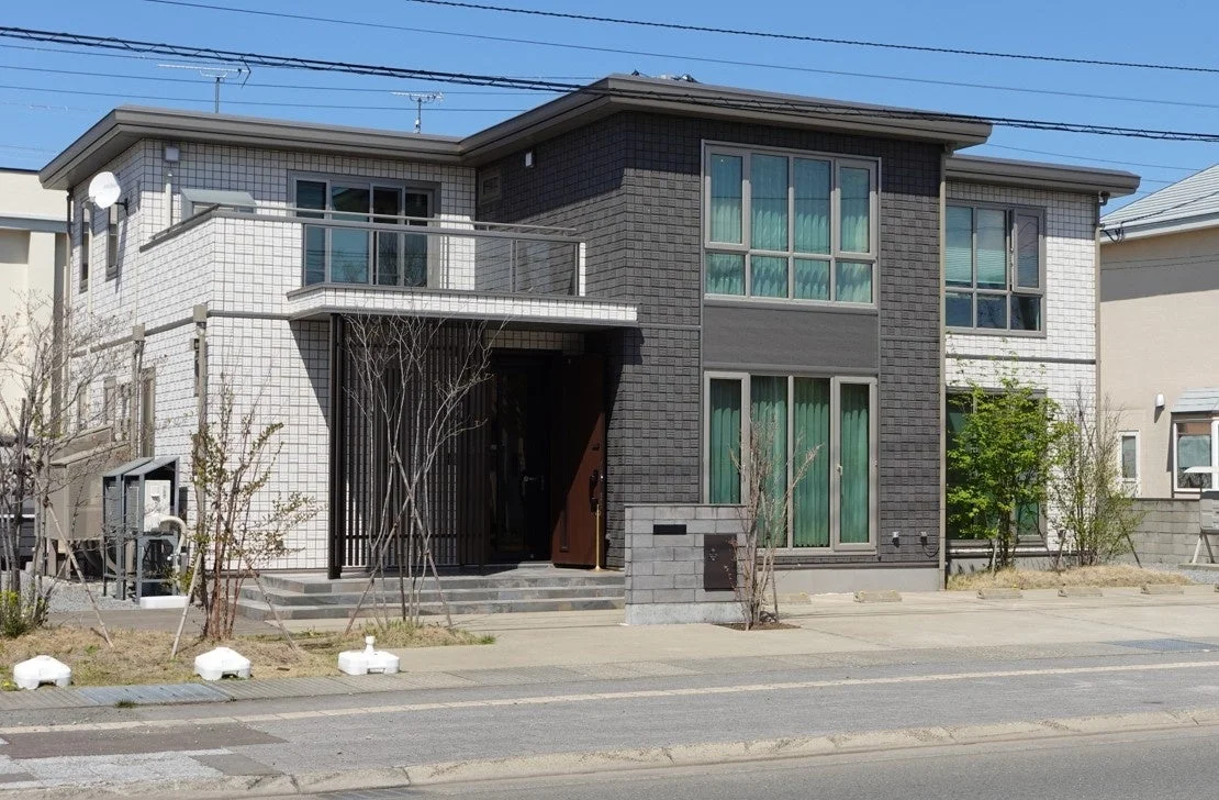 白と濃いグレーの外壁が特徴的なモダンな2階建て住宅