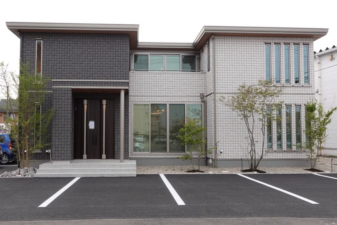 ダークグレーと白のタイル張りの壁が特徴的なモダンな二階建て戸建て住宅