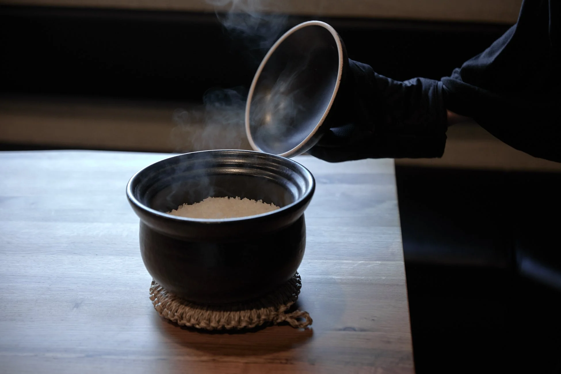 木製のテーブルに置かれた黒い器から白い湯気が立ち上る