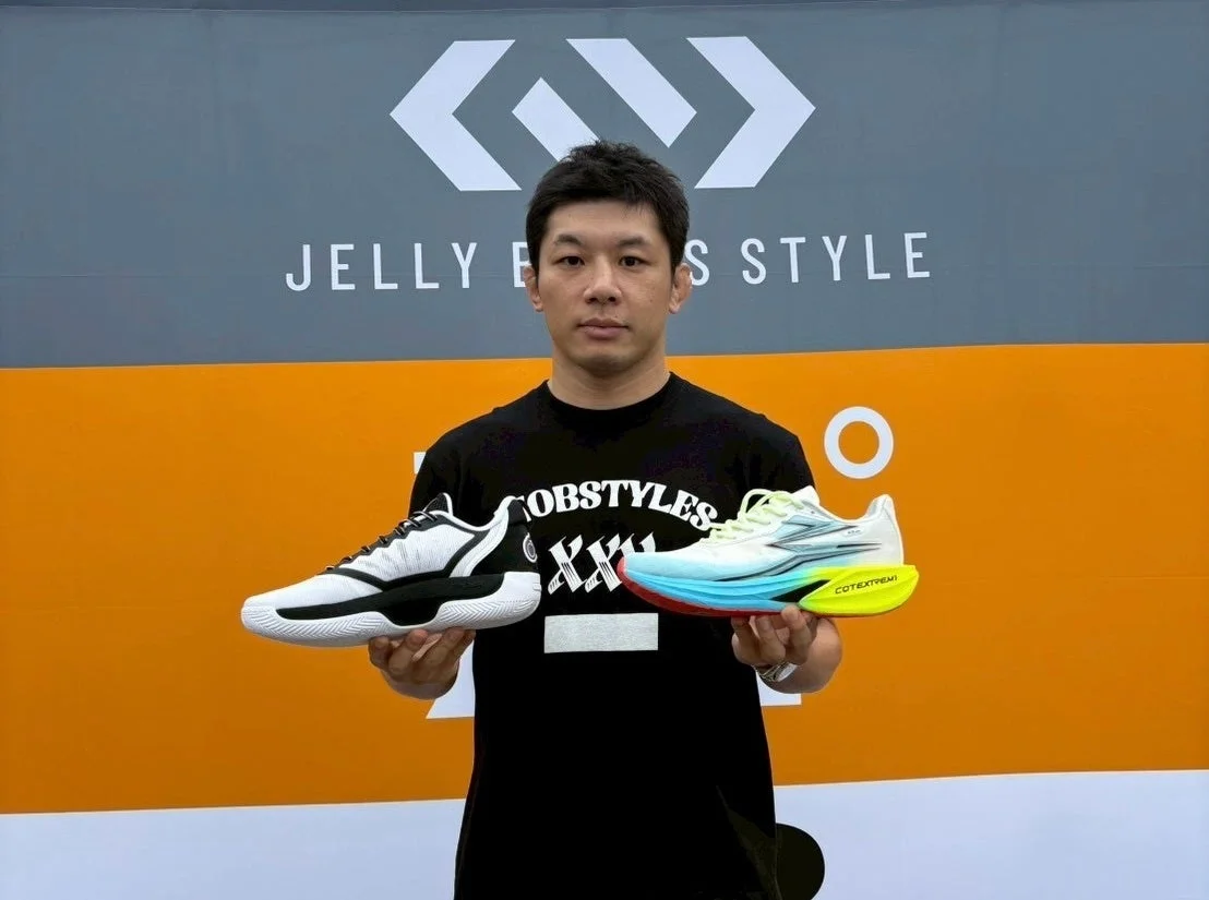 男性がスポーツシューズを持ってポーズをとる