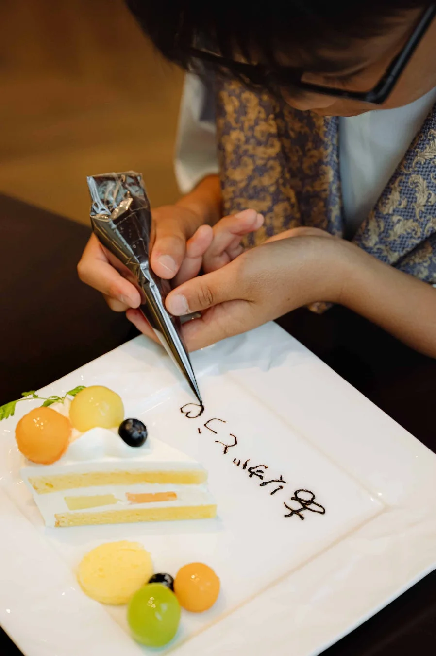 フルーツケーキにチョコレートソースでメッセージを書く様子