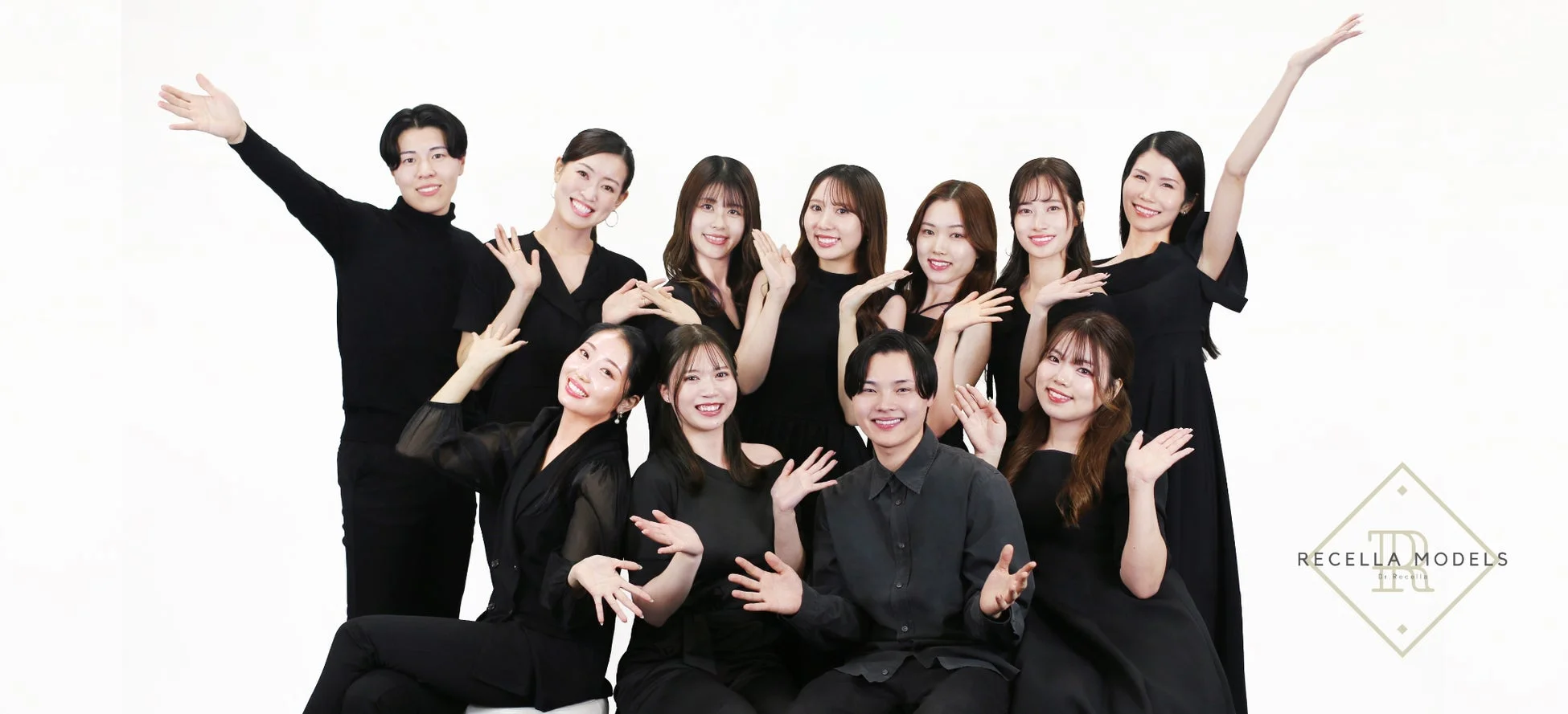 黒い衣装を身につけた10人のモデルが笑顔でポーズをとっている集合写真