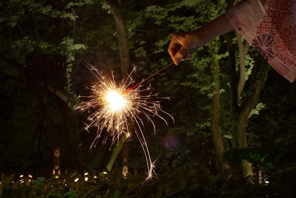 夜の暗闇の中、浴衣を着た人物が線香花火を楽しんでいる様子