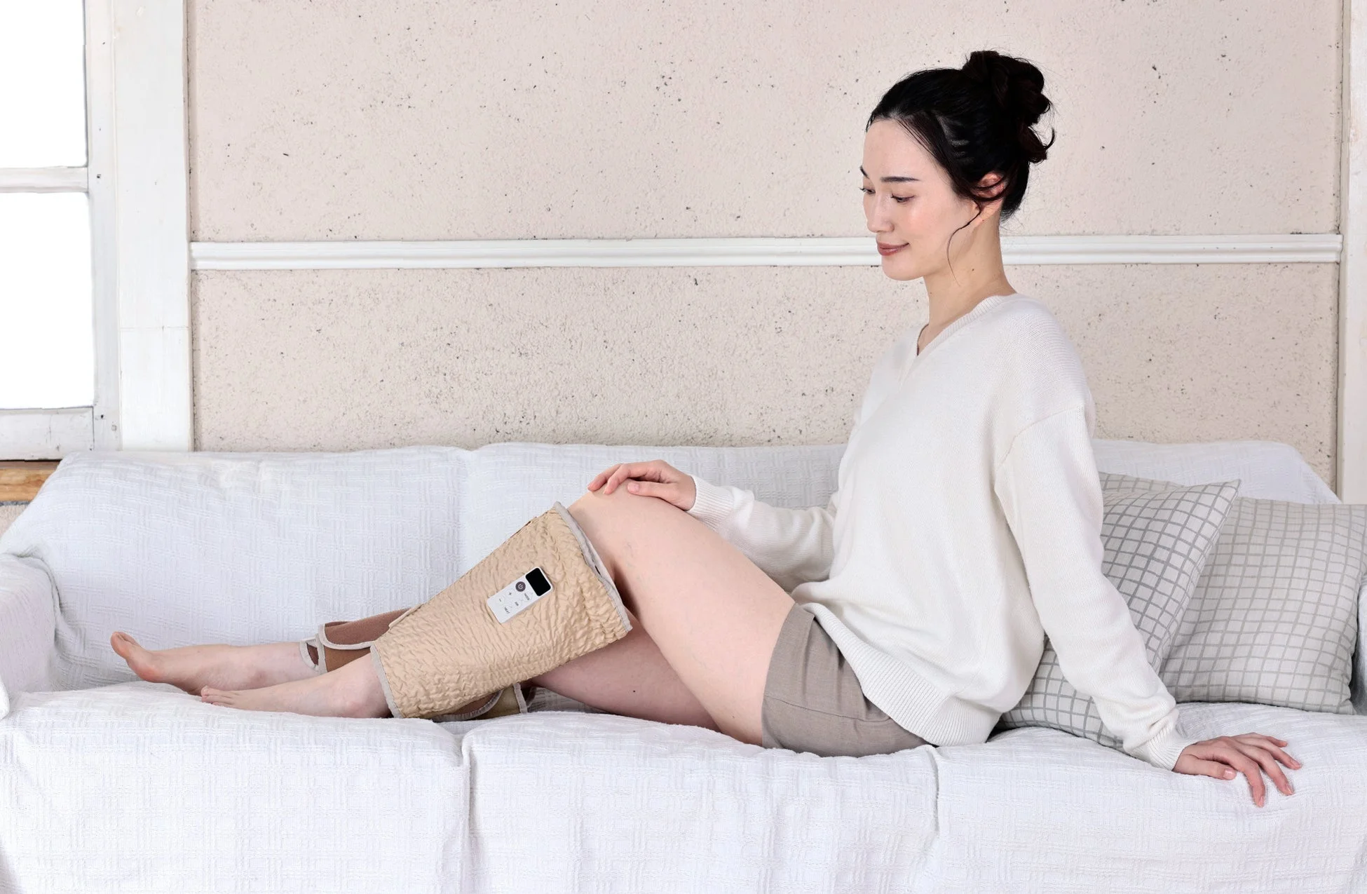 ソファでレッグマッサージャーを使用する女性