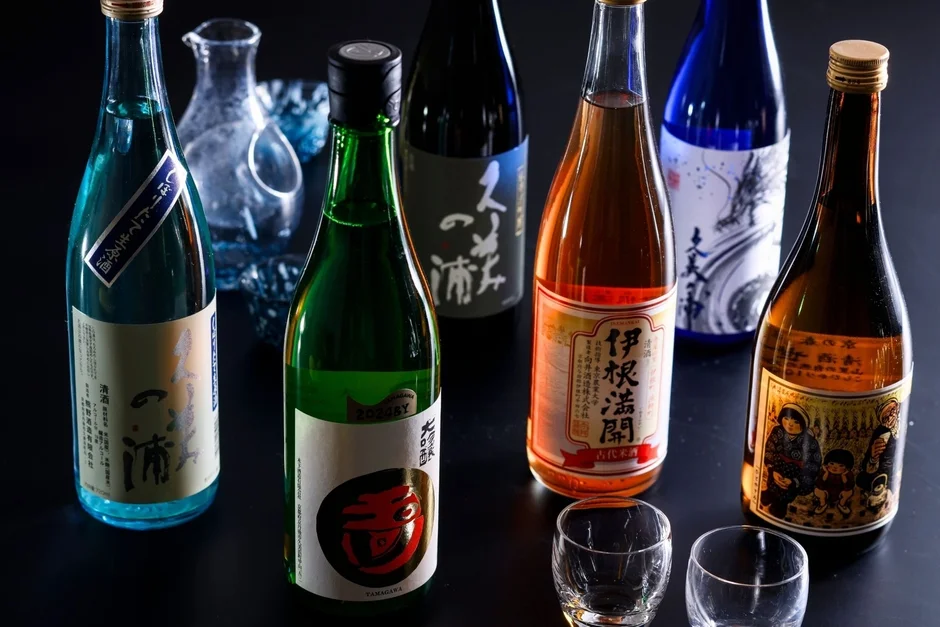 様々な色やラベルデザインの日本酒ボトルが複数並べられている