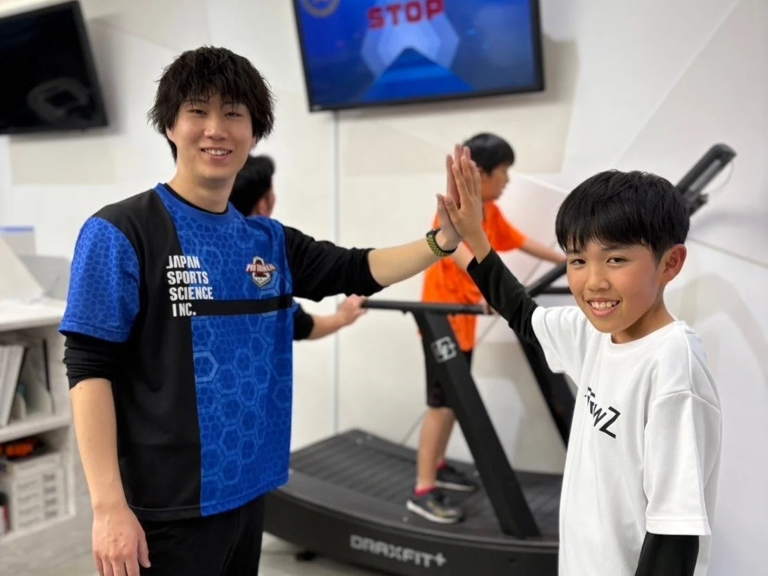 トレーナーとハイタッチする少年