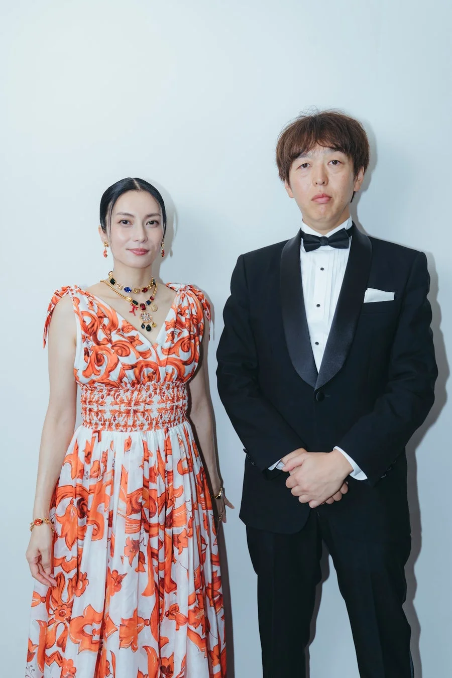 華やかなオレンジ色のドレスを着た柴咲コウ氏と黒いタキシード姿の藤野良太氏