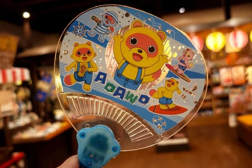 アライグマ風の可愛いキャラクターがマリンスポーツを楽しむ透明なうちわ