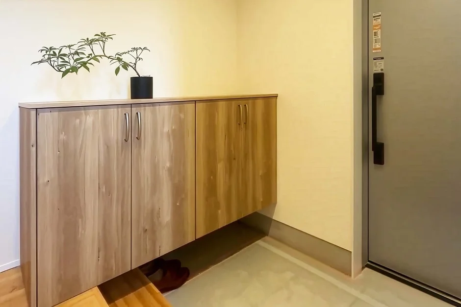 木目調の吊り下げ式玄関収納が設置された、すっきりとした玄関の風景