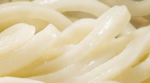 白い麺がクローズアップで写されており、つるつるとした表面と丸みを帯びた形状が特徴的です。おそらくうどんと思われ、食欲をそそるような見た目です。