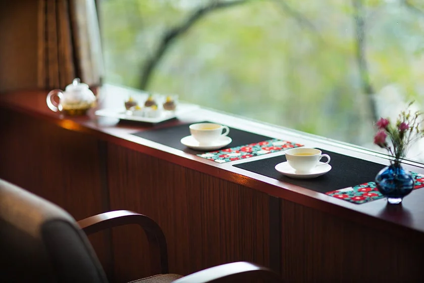 窓辺で温かいお茶とデザートを楽しむ穏やかなティータイム