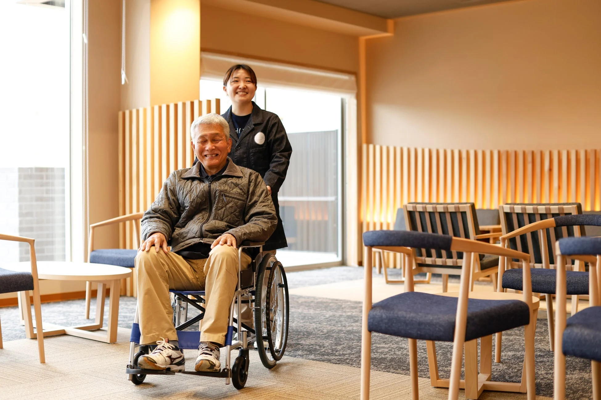 車椅子に乗った高齢の男性と笑顔の介護士