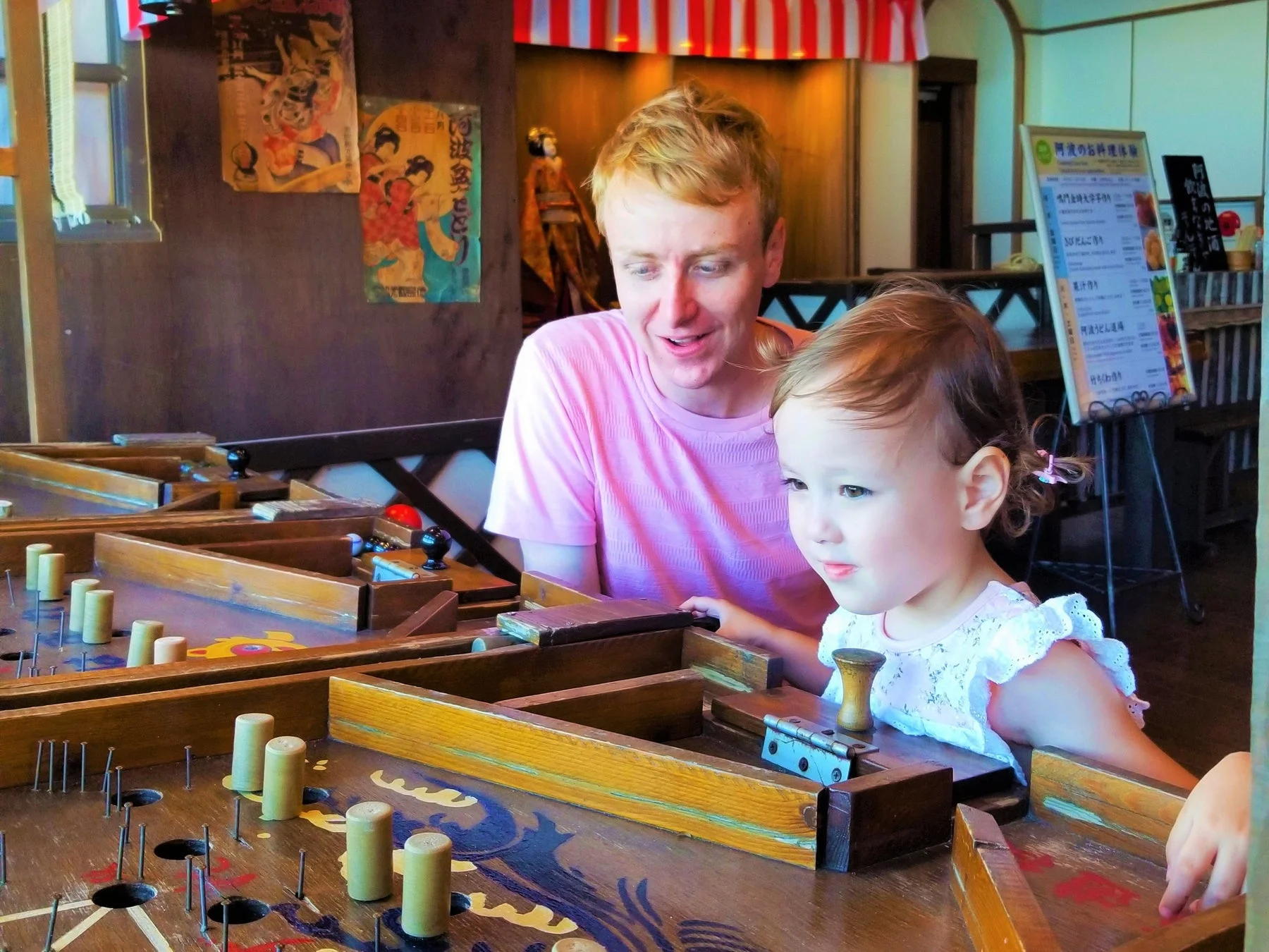 日本の伝統的な木製パチンコのようなゲームで遊ぶ男性と子供