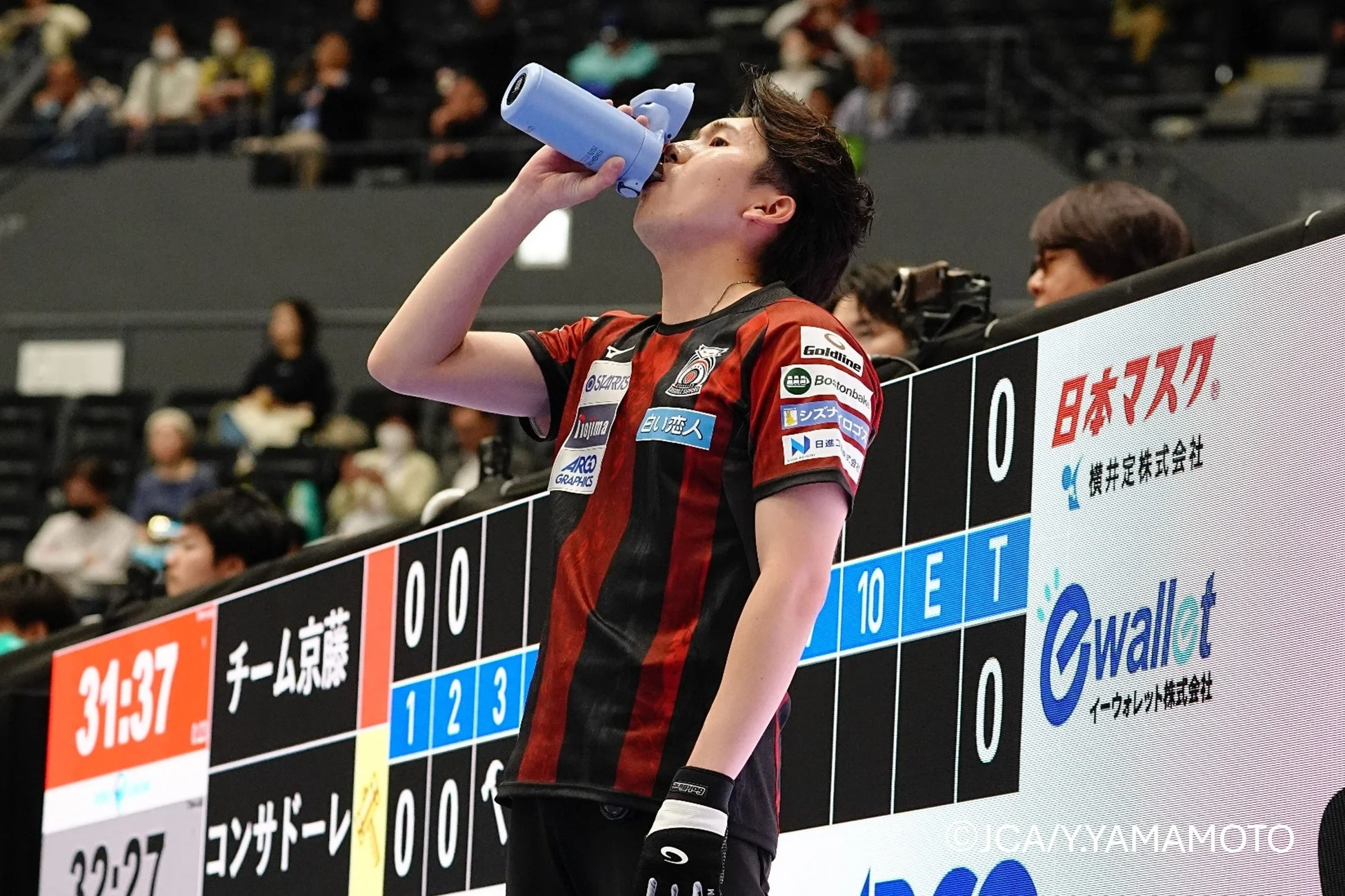 赤いユニフォームの男性アスリートが水分補給