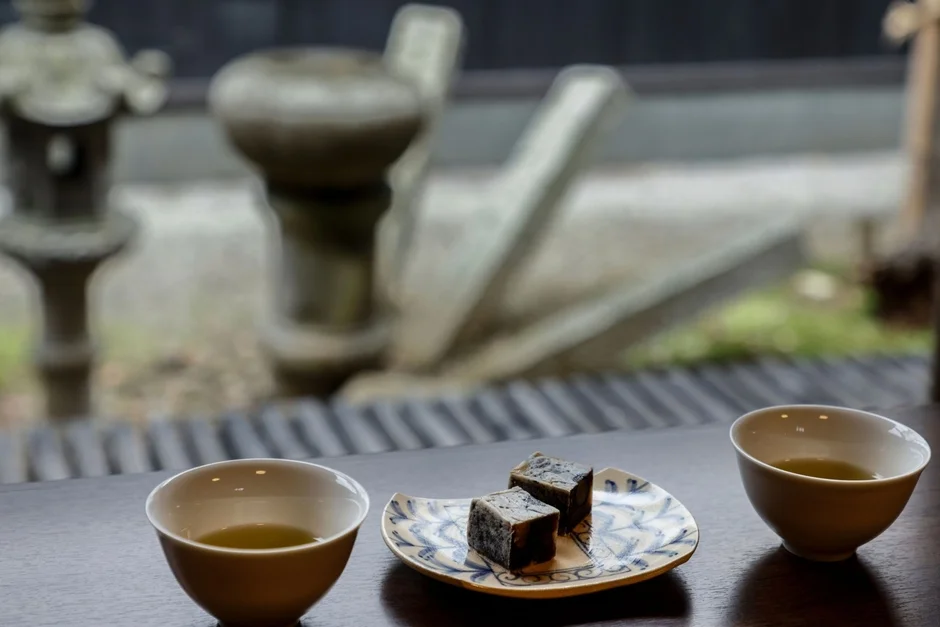 窓辺で日本庭園を眺めながら、お茶と和菓子を楽しんでいる様子