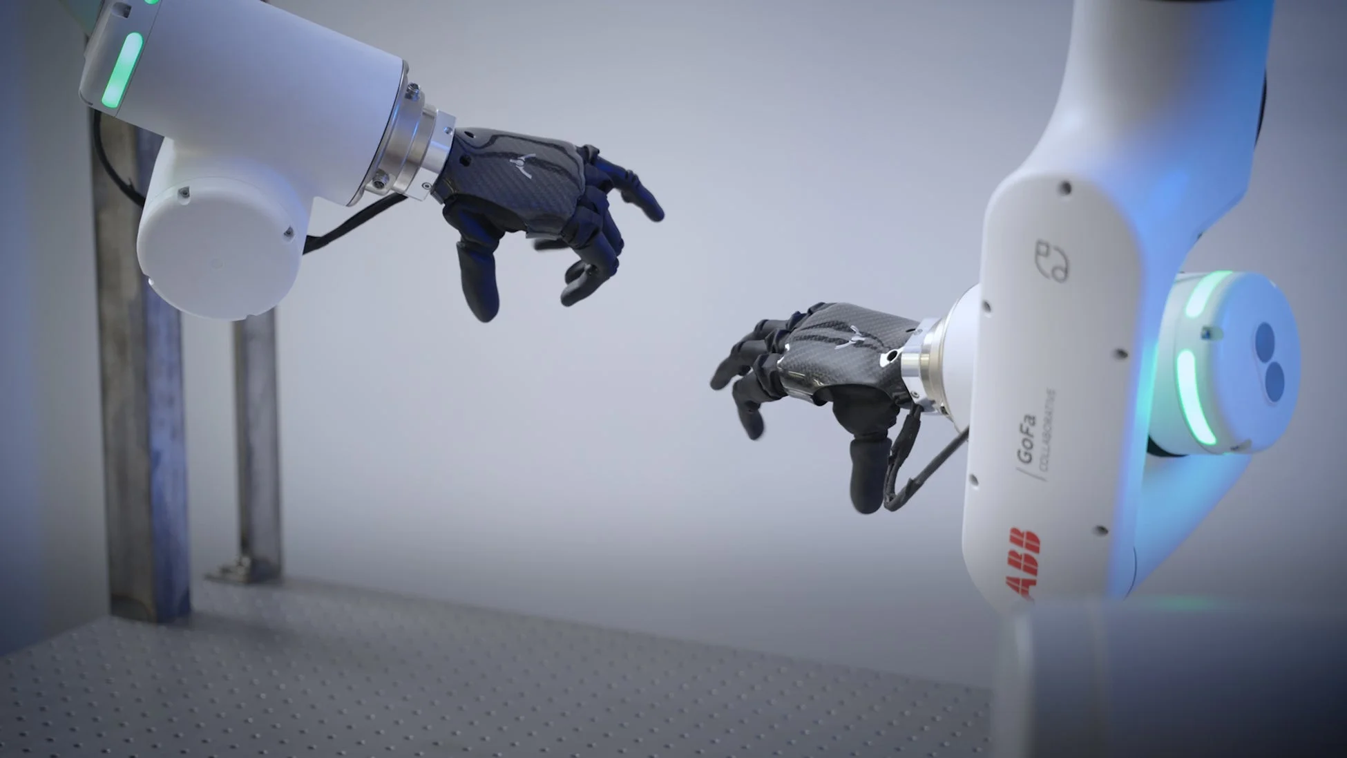 2台の白いロボットアームが、それぞれ黒いカーボンファイバー製のロボットハンドを装着し、互いに向き合うように配置されています。未来的なデザインが特徴で、現代の技術と自動化を象徴する場面です。