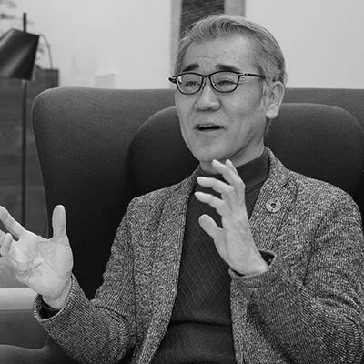眼鏡をかけたシニアの男性が身振り手振りを交えて話す様子