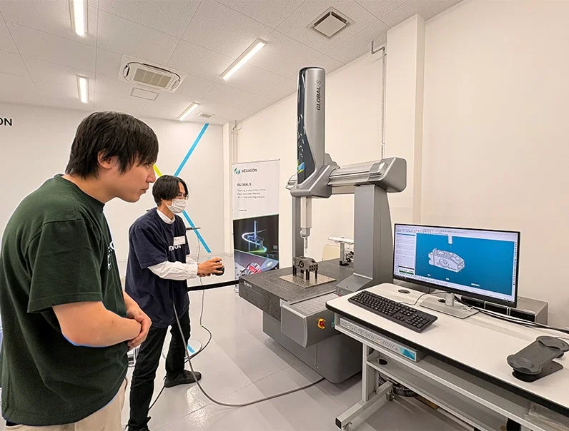 二人の男性が最新の産業用座標測定機を操作・観察している様子