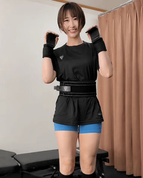 ウエイトリフティングベルトとリストラップを着用し、黒いスポーツウェアを着た女性