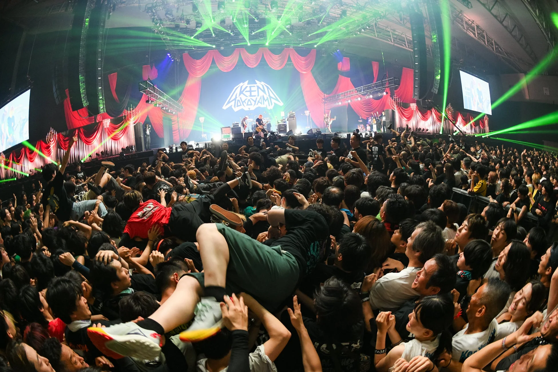 大勢の観客で埋め尽くされたライブ会場で、バンドが熱演している様子