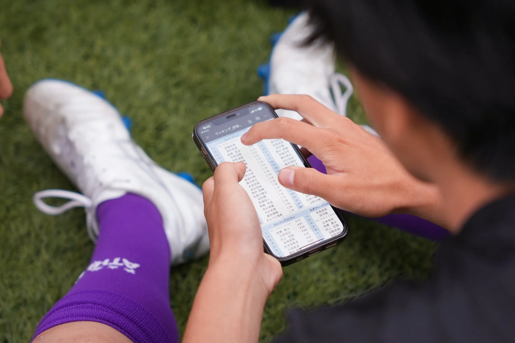 スマートフォンでスプリントやアジリティのランキングデータを確認するサッカー選手