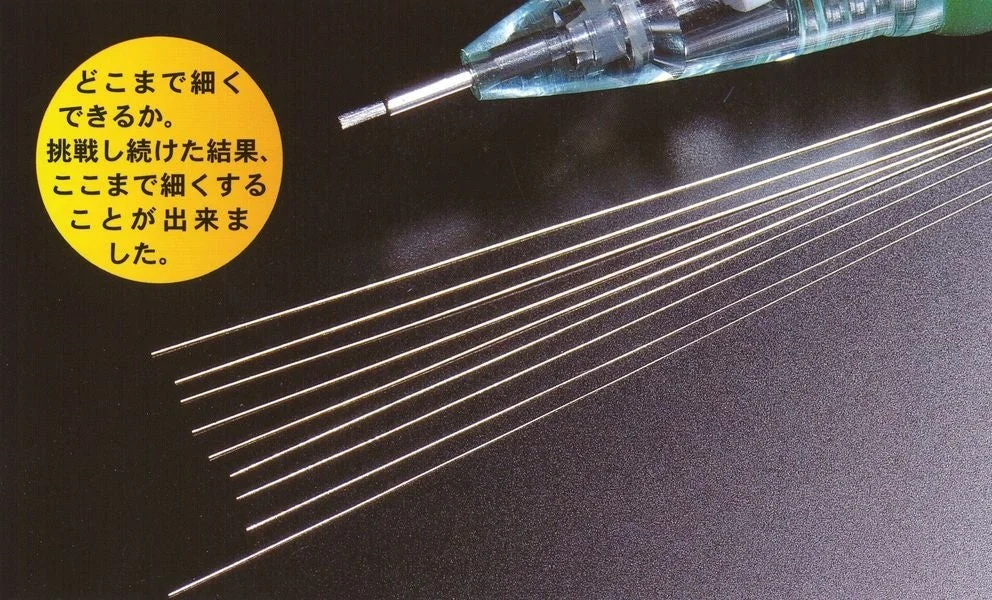 極細の金属線と機械部品が写る画像。