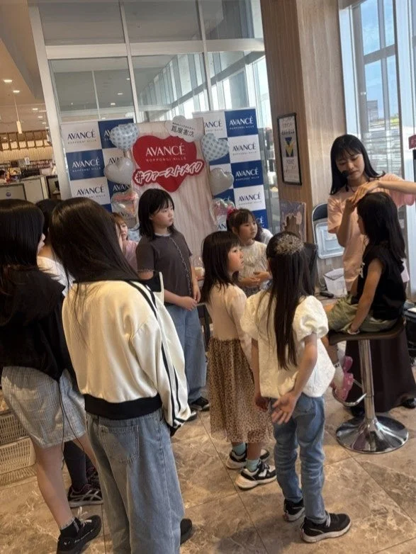 六本木ヒルズのAVANCEで開催された子供向けのファーストメイクイベントの様子。女の子たちがヘアメイクを体験しており、会場は多くの人で賑わっています。