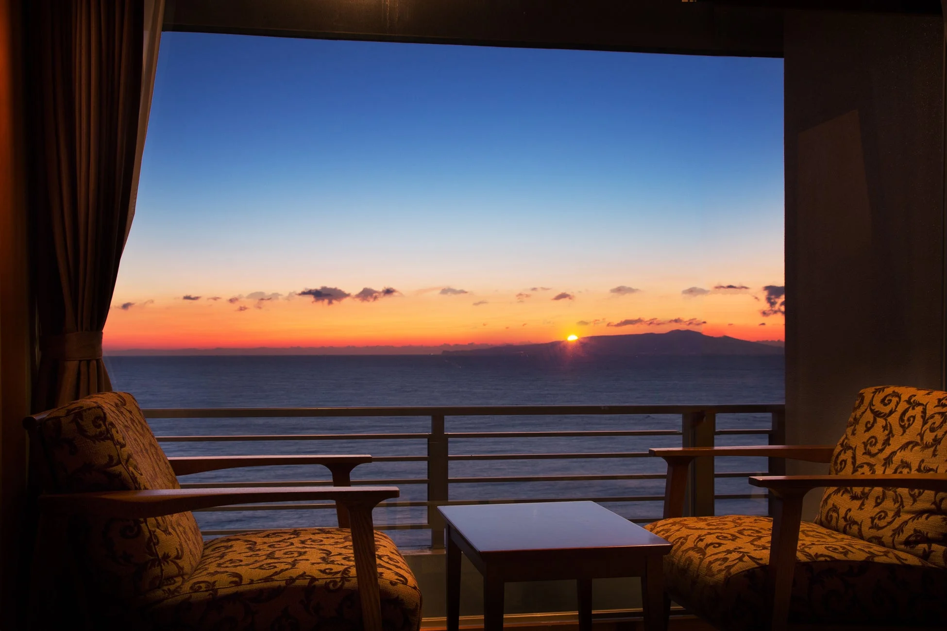バルコニーから望む、海に沈む(または昇る)夕日(または朝日)の美しい景色