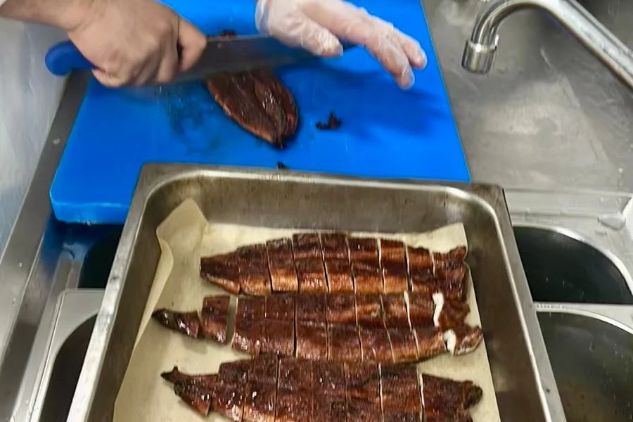 調理場で焼き魚をカットする様子