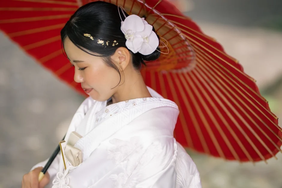 白無垢の女性が赤い和傘を持つ