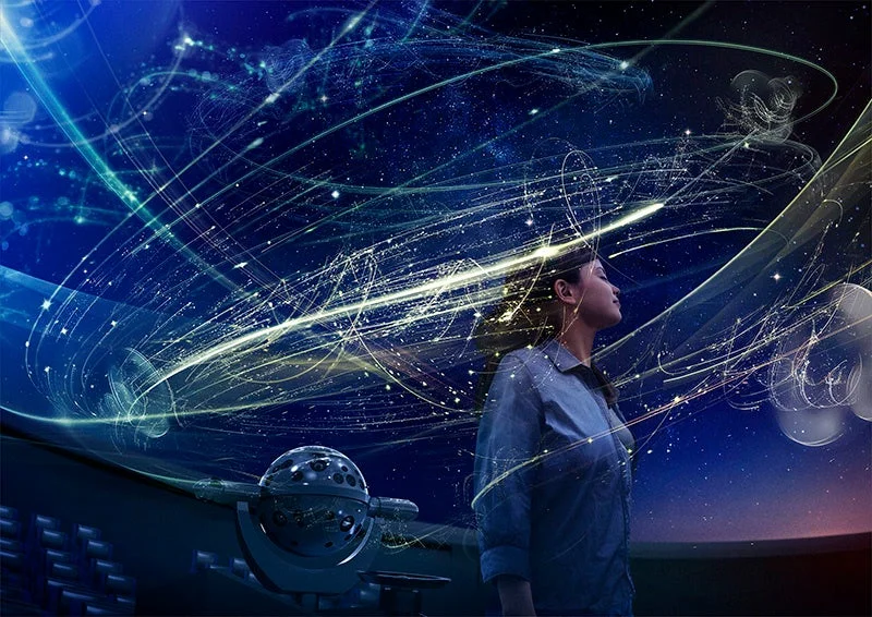 プラネタリウムのような空間で、女性が光の軌跡と星々が織りなす幻想的な景色を見上げています。