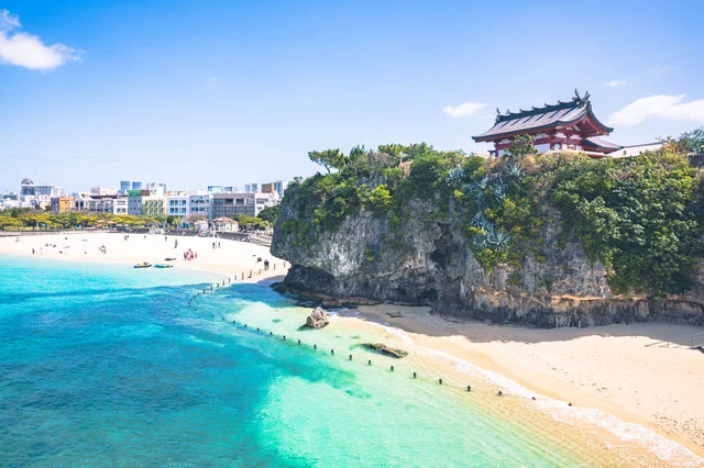沖縄の美しいビーチとエメラルドグリーンの海、伝統的な赤瓦の建物