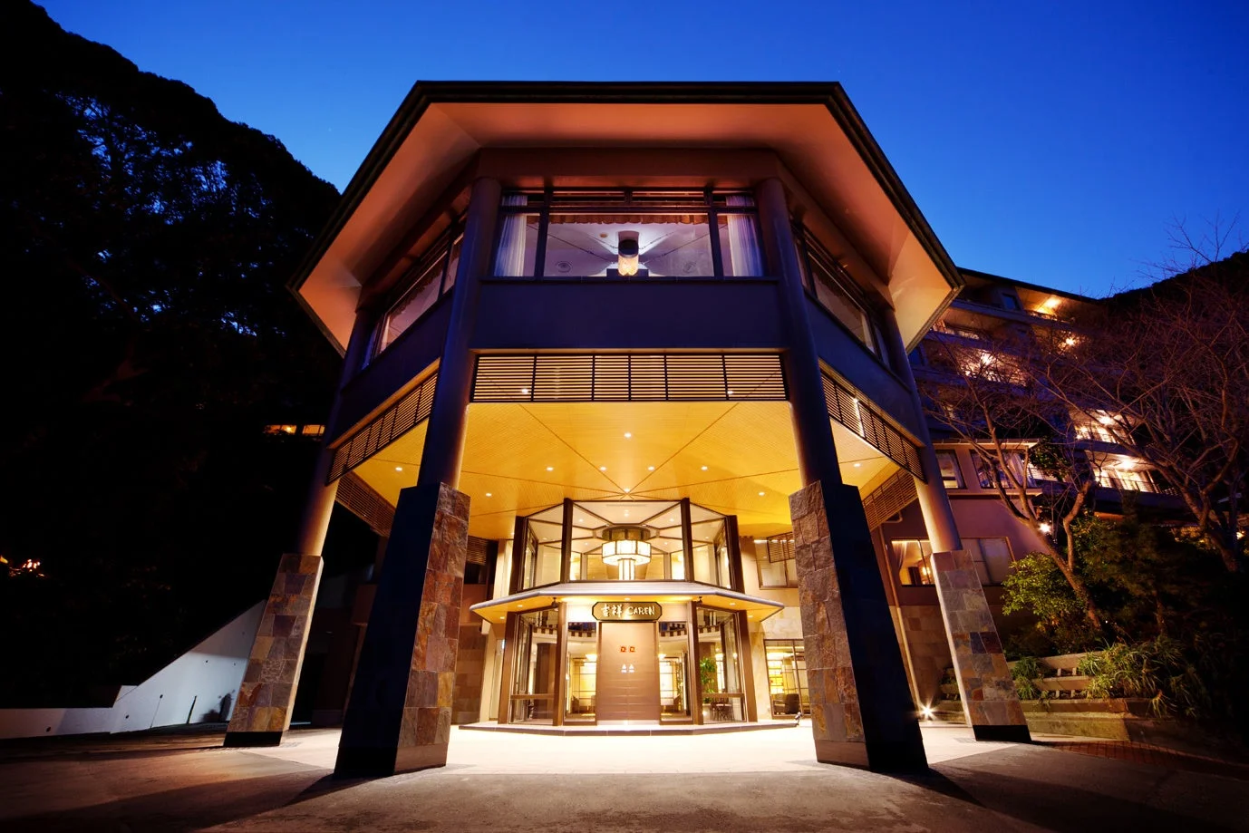 夕暮れ時、暖かくライトアップされたモダンなデザインのホテルのエントランス