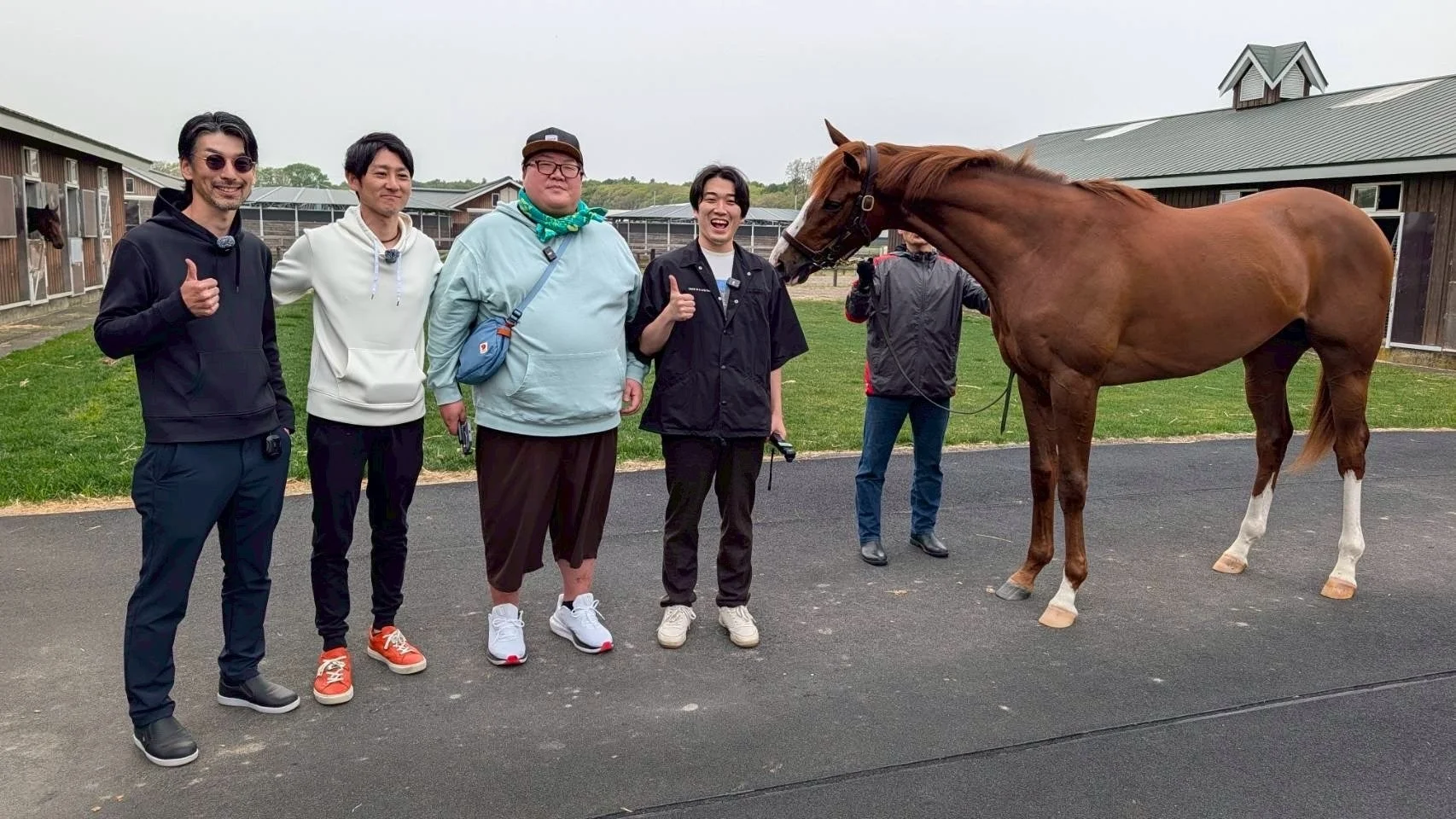 男性数名が厩舎の前で馬と一緒にポーズをとっている写真