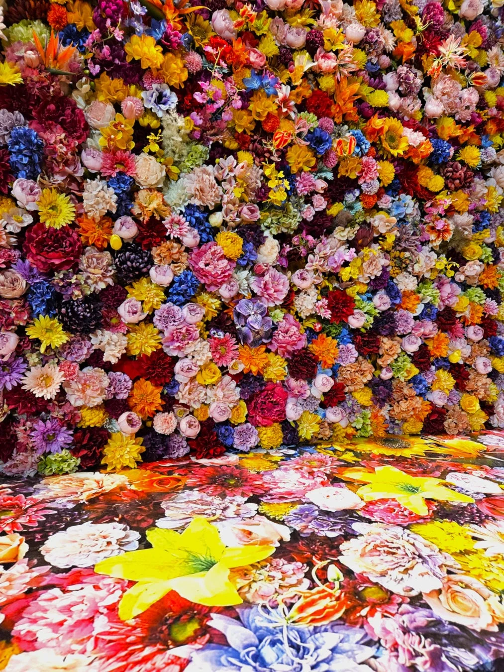 壁一面から床まで、多種多様な色鮮やかな花々で埋め尽くされた空間。まるで花畑の中にいるような、華やかで没入感のある装飾が特徴です。