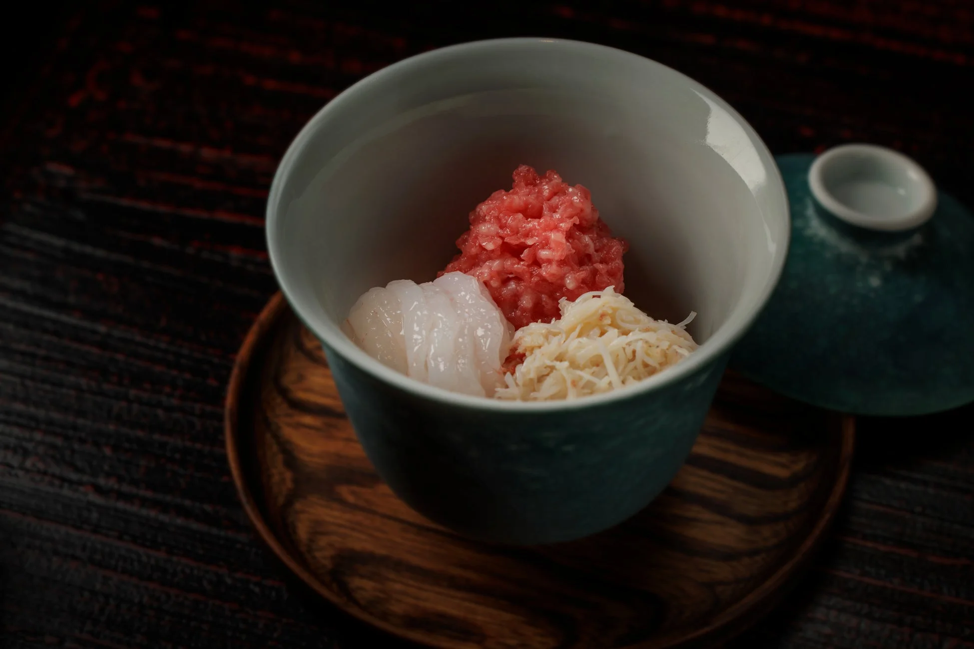 深い色の器に盛られた、赤、白、薄黄色の3種類の食材が特徴的な料理