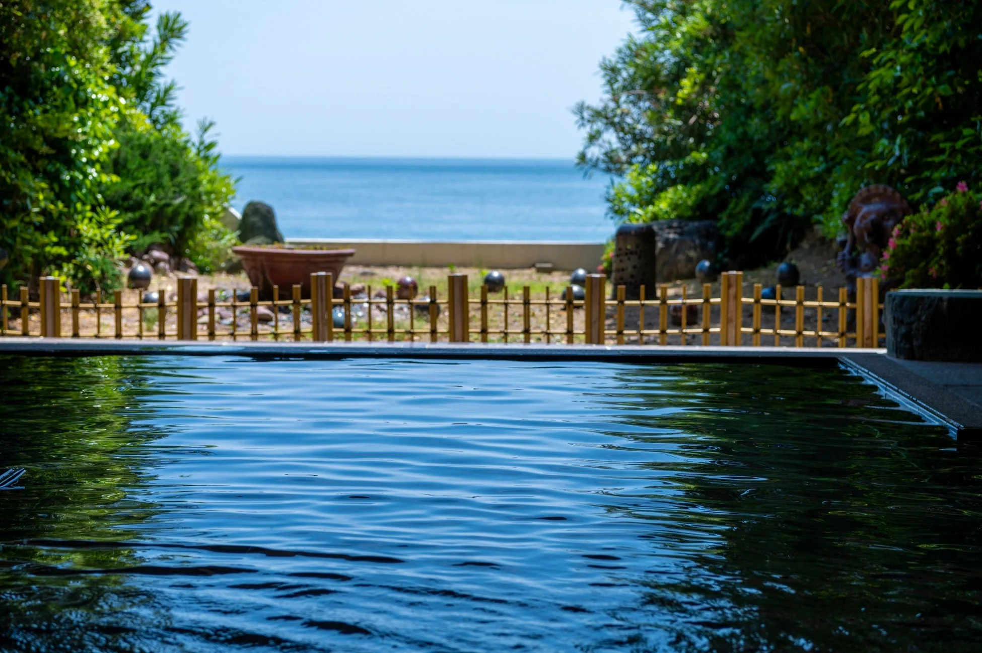 青い水が張られたプール越しに海が見える風景