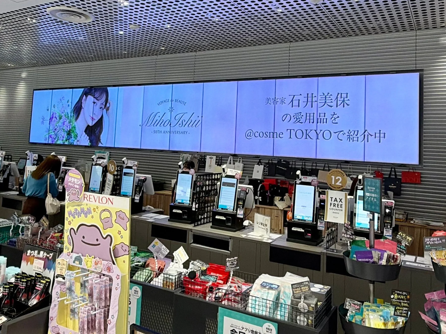 @cosme TOKYO店内の様子を捉えた写真。美容家・石井美保氏の愛用品紹介イベントが開催されており、レブロンのメタモンコラボ商品や免税カウンターも見えます。