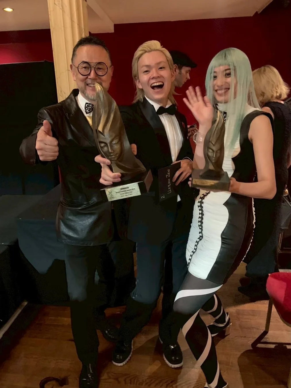 授賞式でトロフィーを手に笑顔を見せる大林氏を含む3人